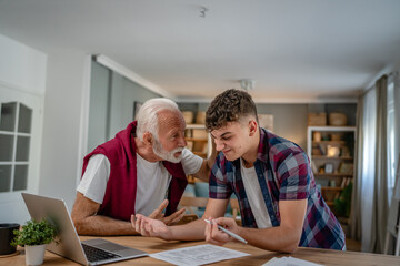 student caucasian male teenager and his grandfather or professor study