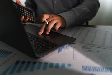 Wall Mural - close-up of a businessman using a computer laptop to analyze finances and calculate investment data paperwork money report tax refund cost Accounting and Banking Concept