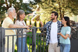 Friendly relationship with neighbours. Young family talking to elderly couple near fence outdoors