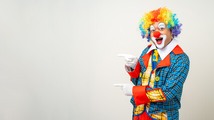 Wall Mural - Mr Clown. Portrait of Funny comedian face Clown man in colorful uniform pointing finger to copy space for text advertise. Happy expression amazed male bozo in various pose on isolated background.