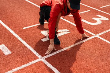 Young handsome indian man doing start pose before running exercise on track in sport stadium. Challenge race of athletes running in the starting point. Young asian man in sport athlete uniform