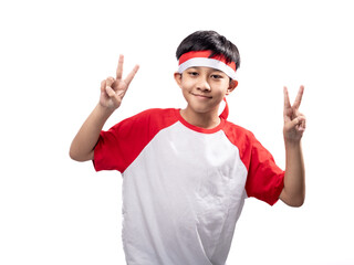 An Asian Indonesian boy wearing a red and white shirt with a headband is posing with a peace sign, raising two fingers upwards, isolated against a white background.