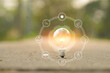 © aekachai - Light bulb Energy saving and a coin glass on the floor nature background