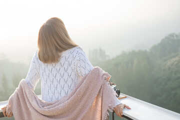 Wall Mural - asian woman stands with her back to camera and enjoys the view of forest. and looking mountain view in morning sunrise with copy space. trip and relaxing. Travel vacations and lifestyle concept.