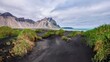In southeastern Iceland, the rippled black sand and grass covered dunes of Stokksnes Beach, with the dramatic peaks of Vestrahorn Mountain in the background.