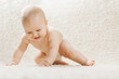 Concept first step infant. Happy baby boy crawling indoors at home on white background