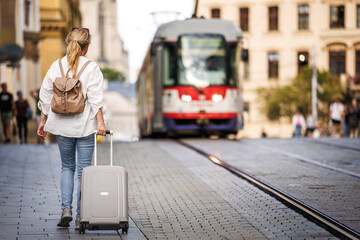 Woman traveler with suitcase and backpack walking on street. Travel and vacation in european city Olomouc, Czech Republic