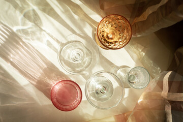 Wall Mural - Various wine glasses and peaches long shadow from the sun on a light beige background. Wine tasting or summer vacation concept. Beautiful fruit background.