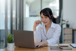 © amnaj - Happy young Asian student woman wearing headphones looking at webcam, looking at camera, during virtual meeting or video call talk.