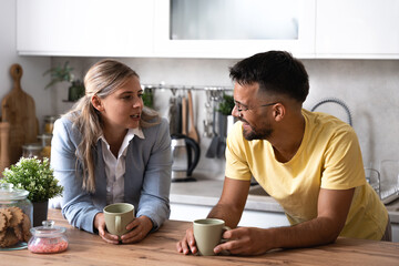 Young man and woman drinking first coffee in the kitchen in the morning, male motivated and wishing luck to his girlfriend at job interview she applied for new business