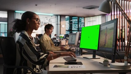 Fototapete - Female Black Game Designer Using Desktop Computer With Green Screen Chromakey on Display, Designing Characters In 3D Modeling Software For Survival Video Game. Woman Working In Game Development Office