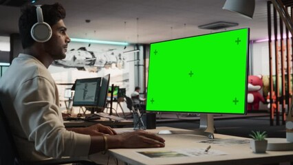 Aufkleber - Portrait of Creative Indian Man Sitting at a Desk Using Desktop Computer with Mock-up Green Screen Chromakey. Male Level Designer Working in Game Design Startup Office, Creating Immersive Gameplay.