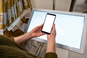 Wall Mural - Woman with phone uses self-service kiosk in the shopping mall.