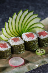 Wall Mural - Delicious tuna sushi rolls served with fresh cucumber slices arranged on marble plate