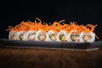 Wall Mural - Row of sushi maki with salmon decorated with shredded carrot served on plate