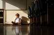 Sad schoolboy sitting alone in classroom