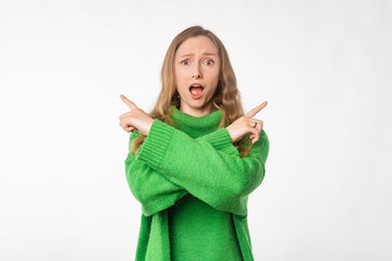 Wall Mural - Portrait of surprised woman pointing pointing sideways, left and right direction, clueless what to choose, making decision, wearing green cozy sweater, standing over white background