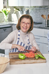 Cheerful woman cutting tomatoes in kitchen