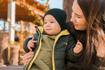 Wall Mural - Cute little asian boy stands outdoors. Happy child walking in autumn park. Toddler baby boy wears trendy jacket and hat. Autumn fashion. Stylish child outside.