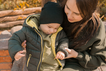 Wall Mural - Cute little asian boy stands outdoors. Happy child walking in autumn park. Toddler baby boy wears trendy jacket and hat. Autumn fashion. Stylish child outside.