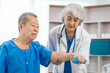 © Phushutter - Asian people mature woman doctor giving male elderly patient through indoor physical therapy in a healthcare wheelchair, emphasizing hands-on support and recovery. expert physical therapy