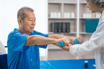 Wall Mural - Asian people mature woman doctor giving male elderly patient through indoor physical therapy in a healthcare wheelchair, emphasizing hands-on support and recovery. expert physical therapy