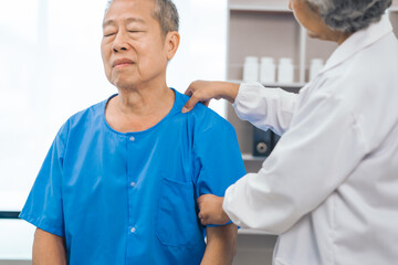 Wall Mural - Asian people mature woman doctor giving male elderly patient through indoor physical therapy in a healthcare wheelchair, emphasizing hands-on support and recovery. expert physical therapy