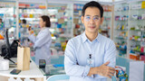 Fototapeta Sawanna - Pharmacy Drugstore. Portrait Professional Pharmacist handsome asian man showing the medicine bottle at pharma store. Health and wellness center
