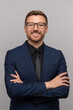© DimaBerlin - Portrait of happy successful confident businessman in suit with crossed arms on chest smiling looking at camera on grey background. Man entrepreneur in eyeglasses on advertisement poster, banner.