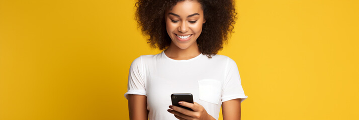 Latin woman wearing a white t-shirt and holding mobile phone looking at smartphone isolated on yellow background