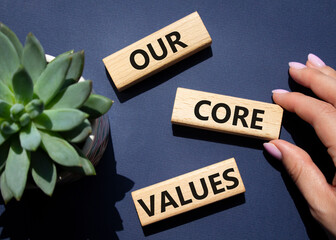 Our core values symbol. Concept words Our core values on wooden blocks. Beautiful deep blue background with succulent plant. Businessman hand. Business and Our core values concept. Copy space.