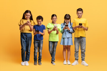 Diverse preteen kids using smartphones on yellow background