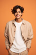 Portrait of happy indian teenager boy looking at camera and smiling while standing on orange background.