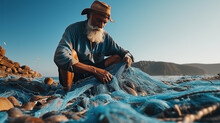 Old Fisherman Hands Sewing Blue Fishing Nets Sitting On The Ground And Surrounded Big Net
