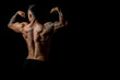 © A Stock Studio - Back view of male bodybuilder with developed body muscles, studio photo on black background. Horizontal banner, copy space.