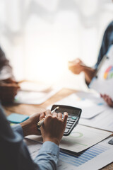 Young colleagues discuss business and analytical price charts using calculators and laptops to calculate financial, tax, accounting, statistics and analytical research ideas.