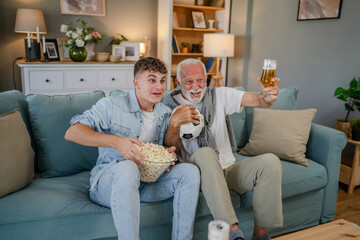 Wall Mural - teenager and his grandfather senior man watch football game at home