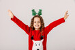 Little girl in red christmas sweater with hands up on white background, christmas holiday concept, happy and emotions