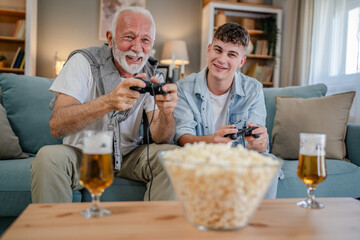 Wall Mural - teenager male and his grandfather senior man play console video game