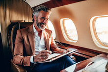 A Businessman Engrossed In A Book While Seated On An Airplane