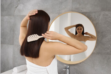 Sticker - Beautiful woman brushing her hair near mirror in bathroom