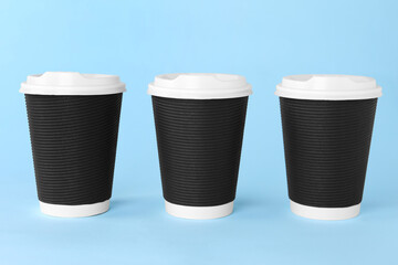 Sticker - Paper cups with white lids on light blue background. Coffee to go