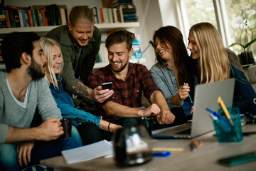 young and diverse group of people using a smartphone while studying in the living room