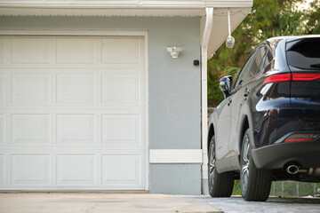 Wall Mural - Car parked in front of wide garage double door on concrete driveway of new modern american house