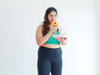 Asian young chubby fat unhealthy oversized overweight plus size female sportswoman in sportswear sports bra legging standing smiling holding eating mixed flavor sweet sugar dessert donuts from plate