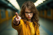 © vefimov - Young girl in yellow jacket pointing directly at camera. This image can be used to represent curiosity, engagement, or call to action.