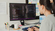 © tirachard - Close-up young Asia girl IT development programmer typing on keyboard coding programming fixing database code on computer monitor and laptop screen on table in workroom at house office.