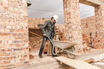 Wall Mural - An experienced worker works on the construction of a brick house