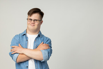 Wall Mural - A smiling young man with cerebral palsy in glasses, jeans and a white T-shirt poses for the camera. World Genetic Diseases Day concept, place for text