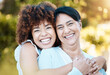 © Anela/peopleimages.com - Happy, portrait and woman hugging her senior mother in nature at an outdoor park in summer. Smile, love and young female person from Mexico embracing her elderly mom with care in a field for bonding.